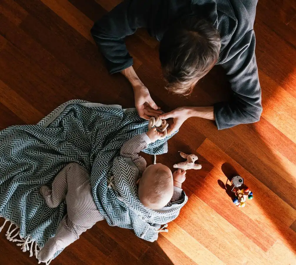 Mother and baby playing on a hardwood floor 